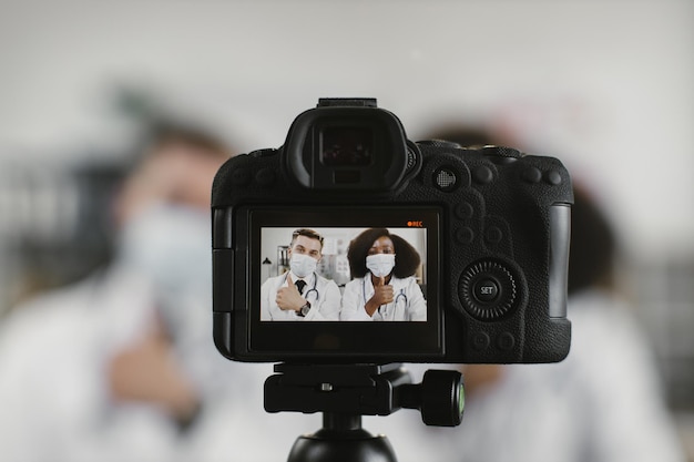Trabalhadores médicos multirraciais em máscaras faciais gravando vlog
