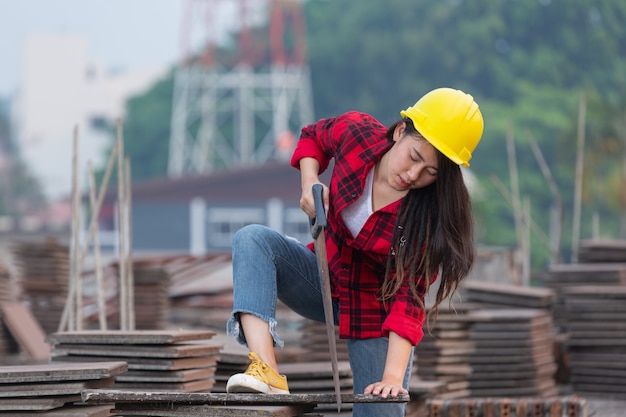 Trabalhadores mulher trabalhadora serrando madeira no canteiro de obras, conceito do dia do trabalho