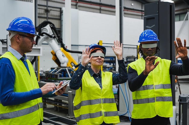 Trabalhadores multirraciais usando tablet digital e óculos de realidade virtual dentro da fábrica robótica