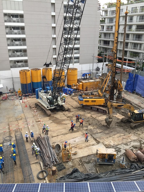 Trabalhadores na área de construção com caminhão guindaste e máquina de retenção