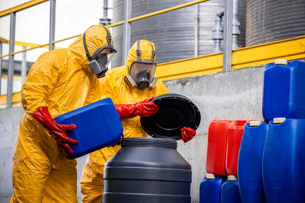 Trabalhadores vestindo traje de proteção e máscara de gás misturando produtos químicos perigosos dentro da planta de produção