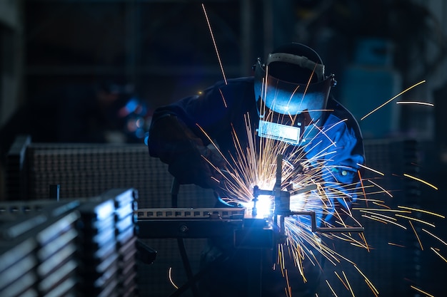 Foto trabalhadores vestindo uniformes industriais e soldada iron mask em plantas de soldagem de aço.