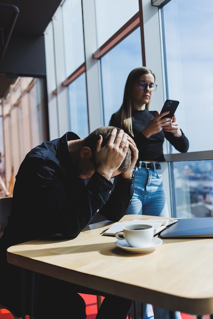 Trabalhamos juntos em um projeto de negócios Dois jovens colegas de trabalho trabalham em um laptop em um grande escritório moderno Parceiros de negócios no escritório no trabalho