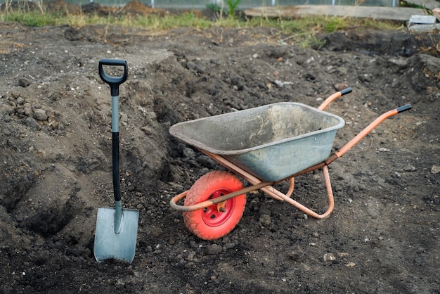 Trabalhando com pá e carrinho de mão de ferramentas de jardim no local de uma preparação de uma casa de campo para