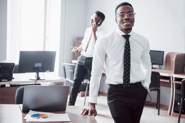 Trabalhando com um sorriso. Heerful empresário Africano em frente a colega.