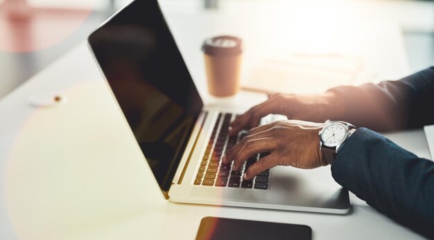 Trabalhando em direção a um prazo Foto recortada de um jovem empresário irreconhecível trabalhando em seu laptop em um escritório moderno