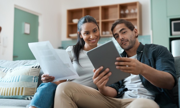 Trabalhando em direção ao nosso futuro um passo de cada vez Foto de um jovem casal cuidando da papelada enquanto usa um tablet digital em casa