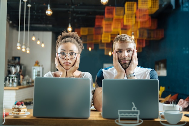 Trabalhando em padaria. dois jovens freelancers modernos trabalhando em uma padaria enquanto tomam algumas sobremesas e café