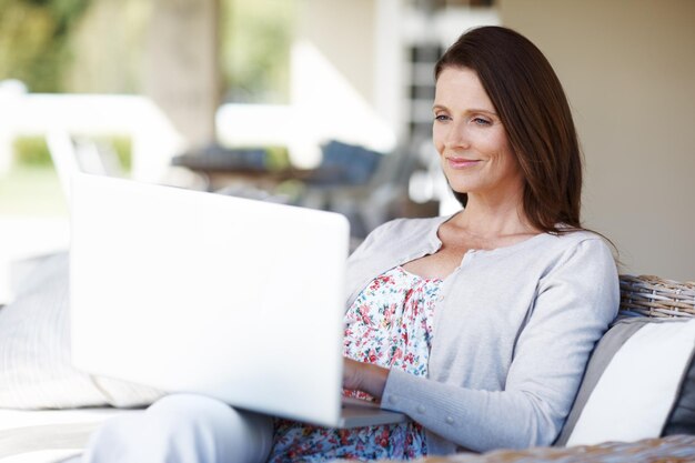 Trabalhando em seu último blog de estilo de vida uma mulher atraente trabalhando em um laptop enquanto está sentada ao ar livre