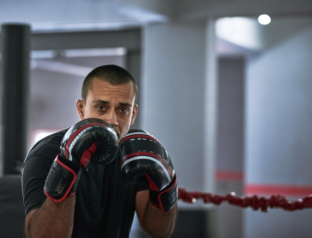 Trabalhando em sua forma Retrato recortado de um jovem atleta masculino treinando dentro de um ringue de boxe