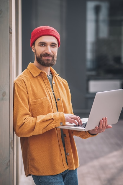 Trabalhando. jovem barbudo com um chapéu vermelho trabalhando em um laptop