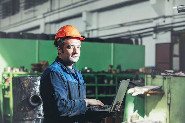 Foto trabalhando na fábrica com um laptop na mão no fundo do equipamento