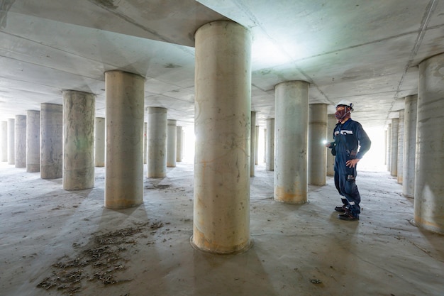 Foto trabalhando pólo de inspeção masculino subterrâneo do túnel de equipamento do tanque usando a lanterna dentro do tanque.