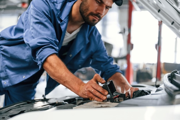 Trabalhando reparando o carro O capô está aberto O mecânico está na garagem O serviço de reparação