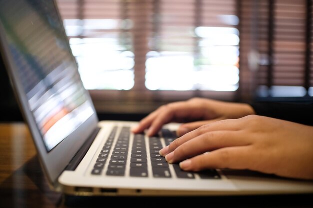 Trabalhando usando um laptop na mesa de madeira Mãos digitando no teclado