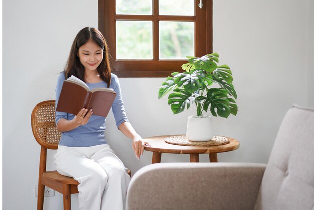 Trabalhar em casa As mulheres de negócios estão sentadas ao lado da janela para relaxar lendo um livro