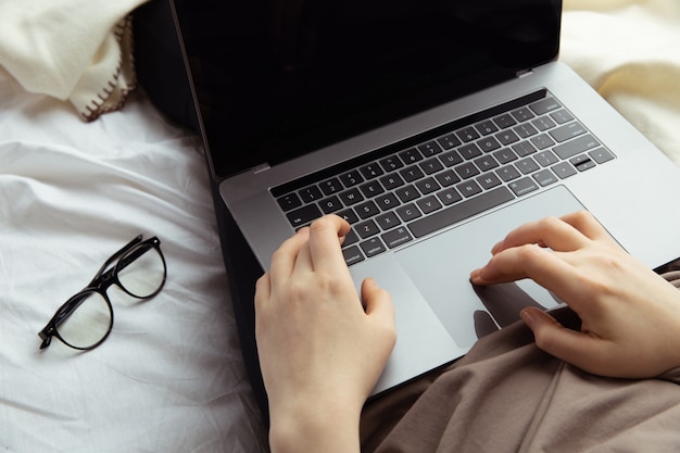 Trabalhe no conceito de casa. Mulher digitando em seu computador na cama.