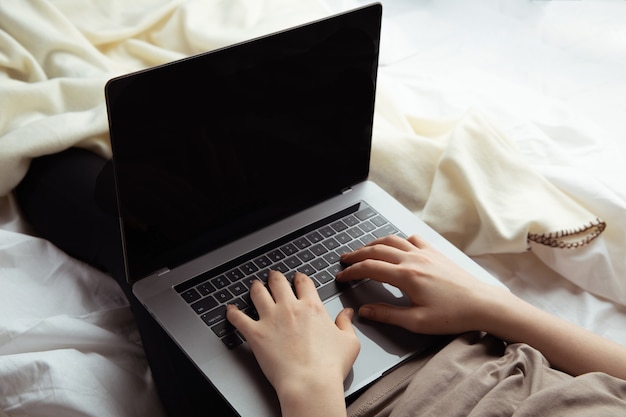 Trabalhe no conceito de casa. Mulher digitando em seu computador na cama.