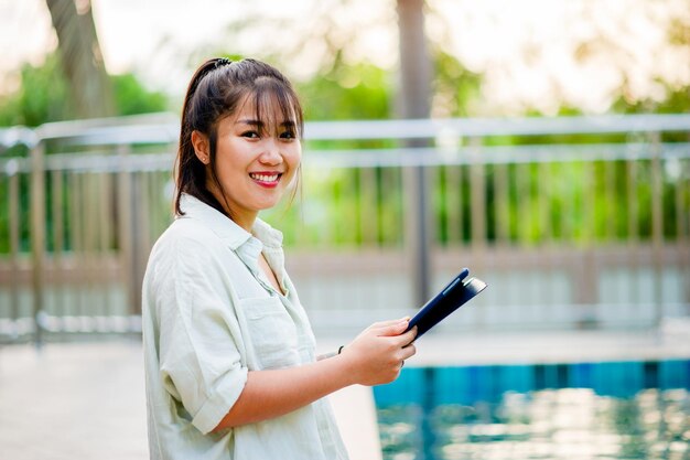 Trabalhe online comunique-se online Jovem mulher com ipad trabalhando com ipad na piscina em casa