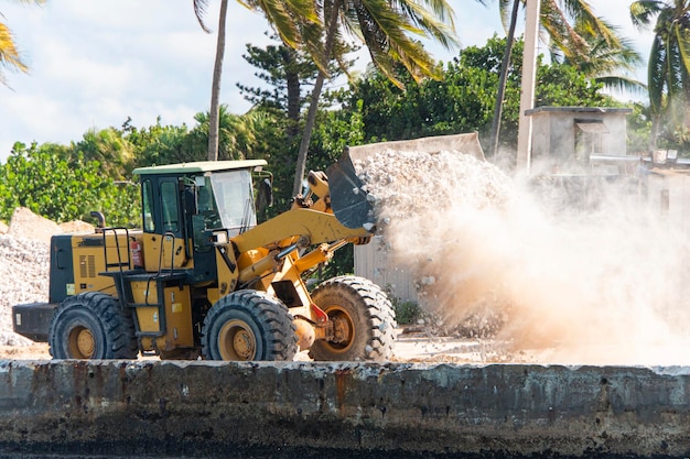 Trabalho da motoniveladora em um canteiro de obras de um edifício carregadeira de rodas escavadeira descarregando areia com obras em movimento de pedra no canteiro de obras