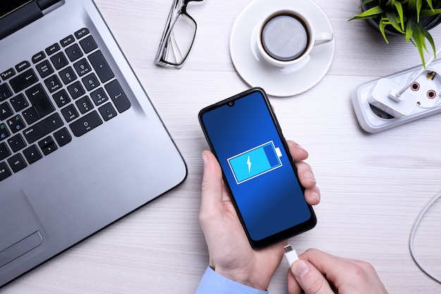 Trabalho de mesa de escritório de madeira Bussines com celular em branco, vários suprimentos. Isso coloca o telefone em carga.