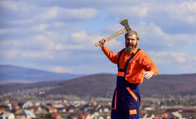 Trabalho duro Ferramentas de renovação Cara bonito temperamento brutal Ocupação profissional Homem de uniforme segura machado Homem barbudo brutal machado nas mãos Construtor brutal e barbudo com machado Use construção de machado