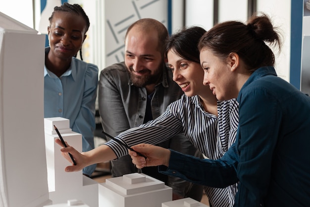 Trabalho em equipe arquitetônica multiétnica analisando maquete