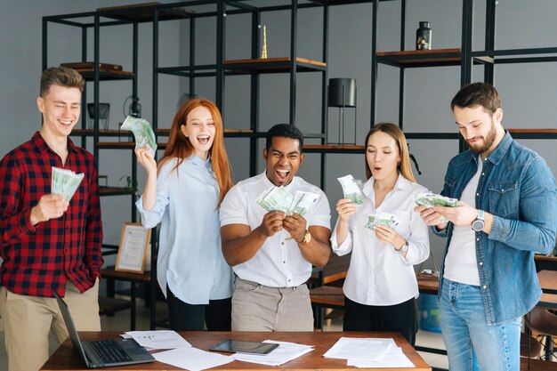 Trabalho em equipe bem-sucedido e empresários felizes segurando dinheiro e sorrindo