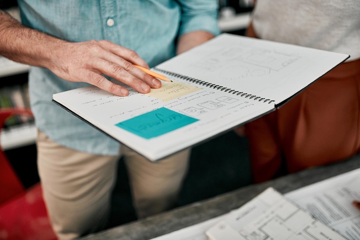 Foto trabalho em equipe de arquitetura e mãos com nota adesiva no escritório para projeto de criatividade e planejamento com livro arquitetos pessoas de negócios ou colaboração com ideias para plano de piso plano ou esboço