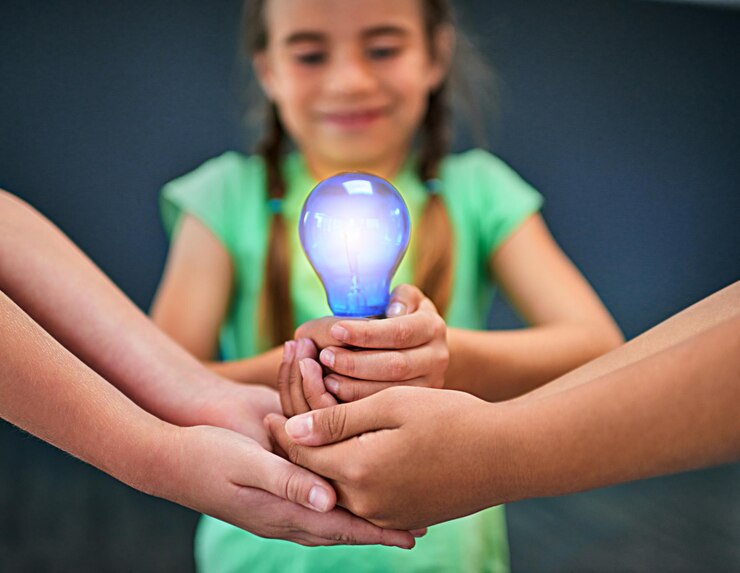 Foto trabalho em equipe de educação e lâmpada com crianças em estúdio para inspiração, aprendizagem e futuro resolvendo problemas, conhecimento e inovação com as mãos dos alunos em fundo para energia elétrica
