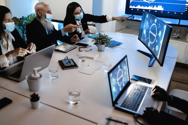 Foto trabalho em equipe fazendo reunião dentro do escritório da empresa fintech usando máscara de segurança durante surto de coronavírus - foco principal na mão direita da mulher