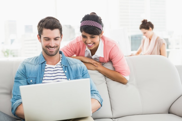 Trabalho em equipe feliz trabalhando em conjunto com laptop