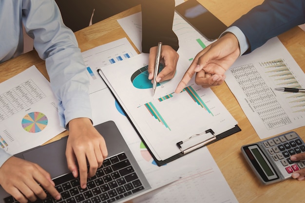 Trabalho em equipe reunião discutindo um novo projeto e mão apontando gráfico na papelada