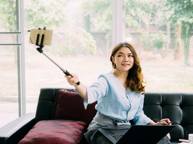 Trabalho em linha do internet da mulher consideravelmente asiática em casa e relaxe o estilo de vida com seu labtop