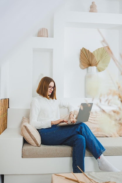 Trabalho freelance e negócios em casa Uma mulher trabalha remotamente em casa em um computador portátil