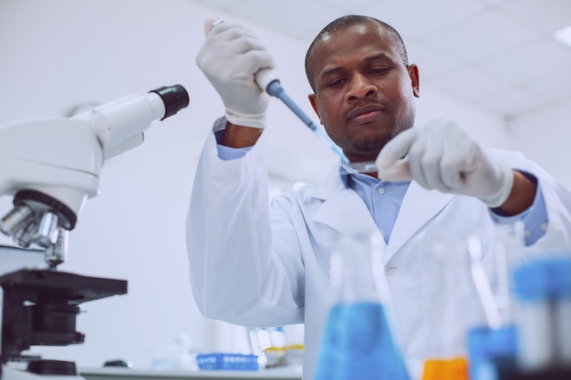 Trabalho interessante. Pesquisador habilidoso concentrado vestindo uniforme e realizando um teste