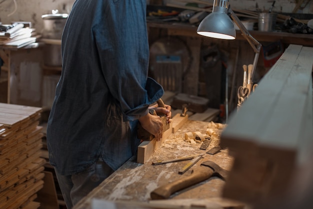 Trabalho manual feminino. Mulher trabalha em uma oficina de madeira. Close de mãos femininas com uma ferramenta