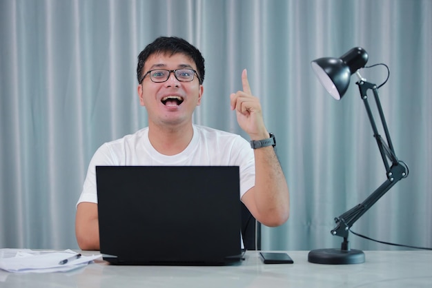 Trabalho remoto de tecnologia e conceito de estilo de vida feliz homem asiático de óculos.