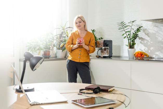 Trabalho remoto em casa. Jovem mulher usando laptop. Freelancer no local de trabalho no escritório da cozinha. Teletrabalho isolado, negócio feminino, compras online. Aluno em EAD. Momento de estilo de vida.