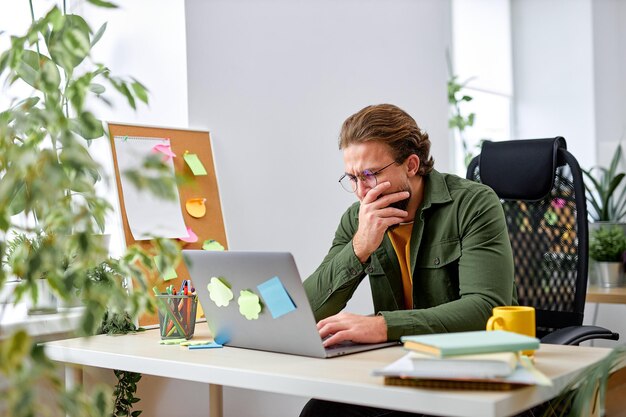 Trabalho remoto, tecnologia e conceito de pessoas. exausto jovem com computador portátil