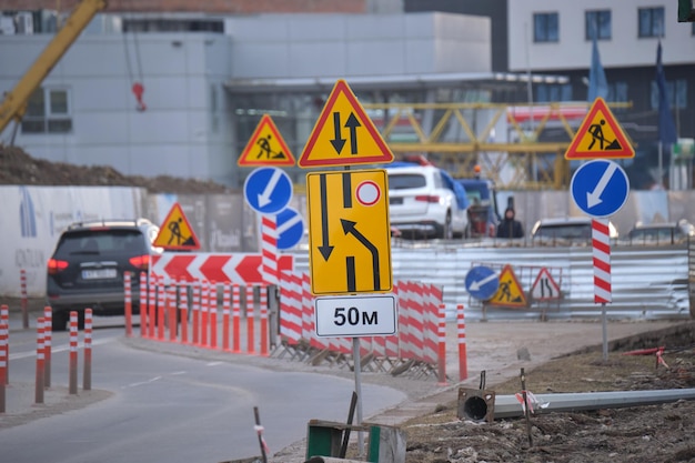 Trabalhos rodoviários avisando sinais de trânsito de trabalhos de construção na rua da cidade e carros em movimento lento