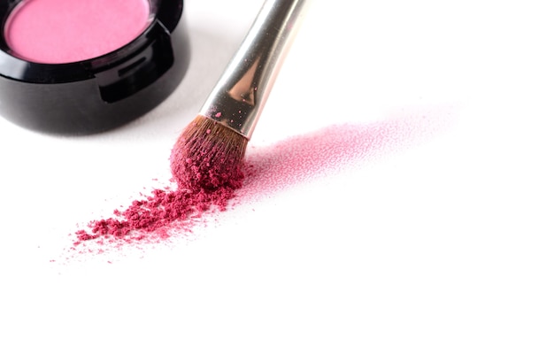 Traço de sombra rosa feito com pincel de maquiagem em papel aquarela e pote de sombra para os olhos isolado em um fundo branco