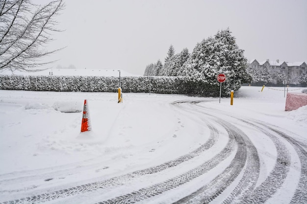 Traços de pneus de inverno na estrada de neve viram com placa de pare na frente