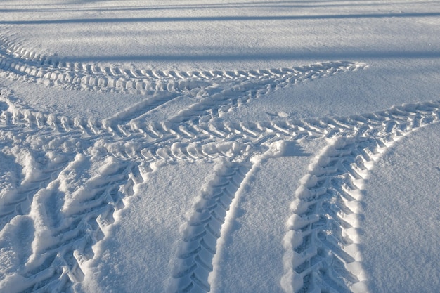 Traços de um trator de rodas na neve no campo. padrões de neve de inverno