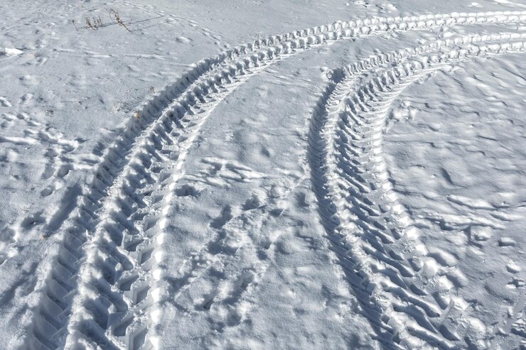 Traços de um trator de rodas na neve Padrões de neve de inverno