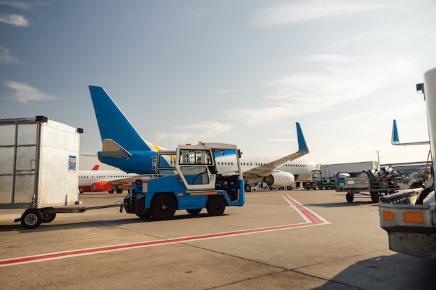 Tractor de aeródromo cerca de gran avión moderno. Preparación de aeronaves en el hub del aeropuerto durante el día. Avión, envío, concepto de transporte
