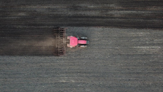 El tractor agrícola ara el campo del suelo para sembrar la vista superior aérea desde el dron