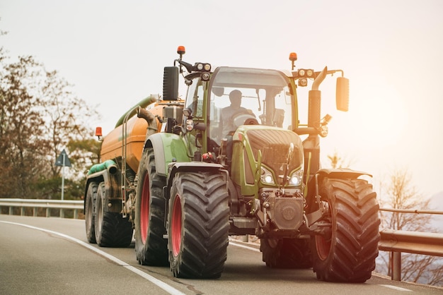 Tractor agrícola moviéndose en el camino rural cerca de la granja