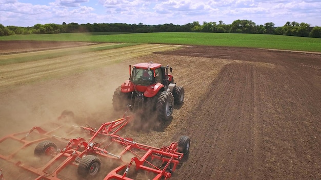 Tractor agrícola con remolque arando en campo agrícola Maquinaria agrícola