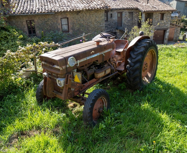 Tractor antiguo restaurado bellamente iluminado estacionado en un campo rural con hierba verde